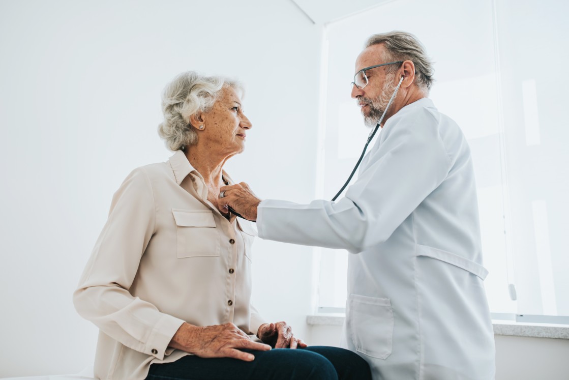 Doctor listening to senior woman patient heartbeat 