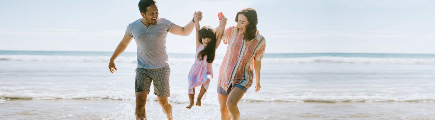 Young couple on beach with their daughter, walking in water