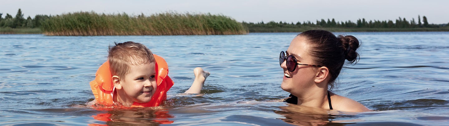 Mom teaching son how to swim in a lake.