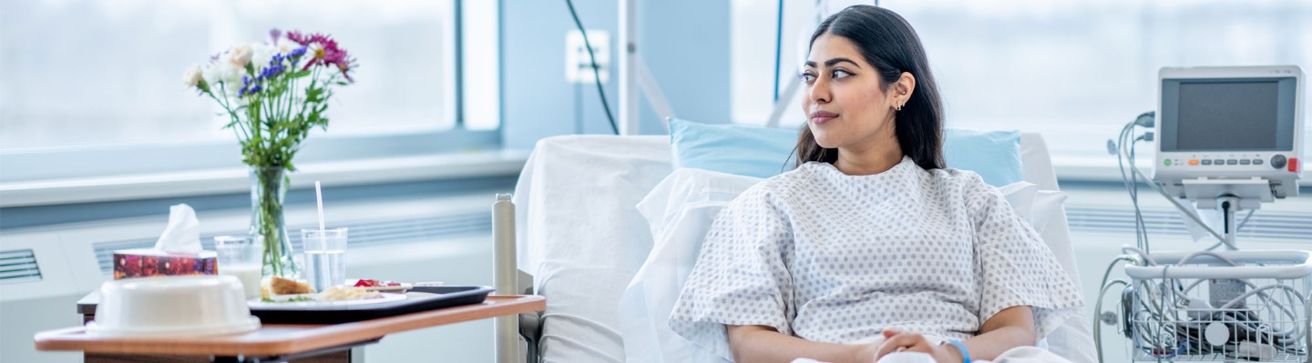 Patient in a hospital room looking at her flowers at her bedside.