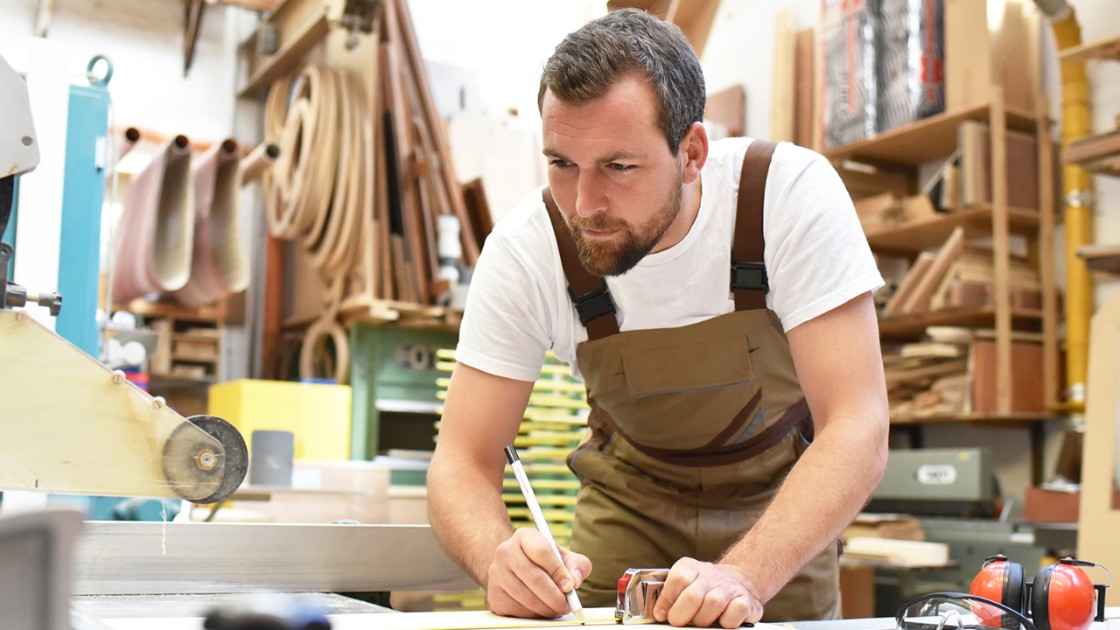 A man measures and trims materials for a woodworking project 