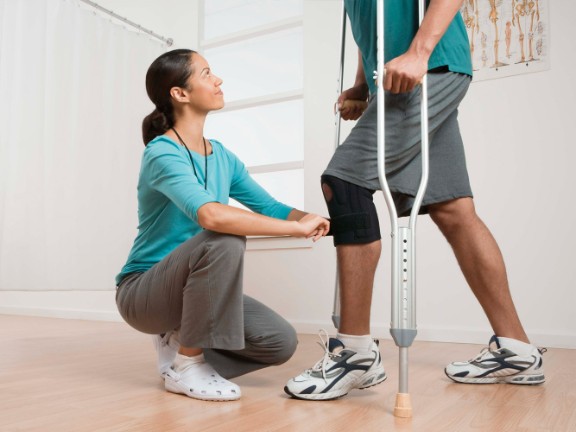 physical therapy with provider helping patient on crutches