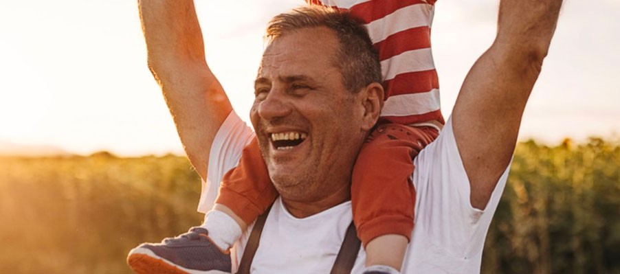 Man holding daughter on shoulders and laughing