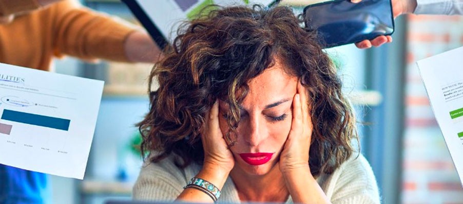 Young woman staring at computer with hands on her cheeks, very frustrated