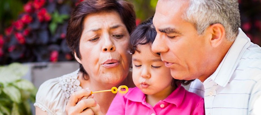 Grandma and Grandpa blowing bubbles with granddaughter