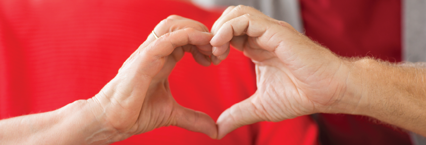 A man and woman hold their hands together in a heart shape to raise awareness of heart health differences between men and women.