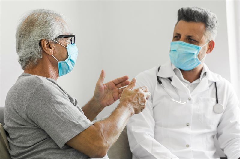 Masked patient talking with masked doctor