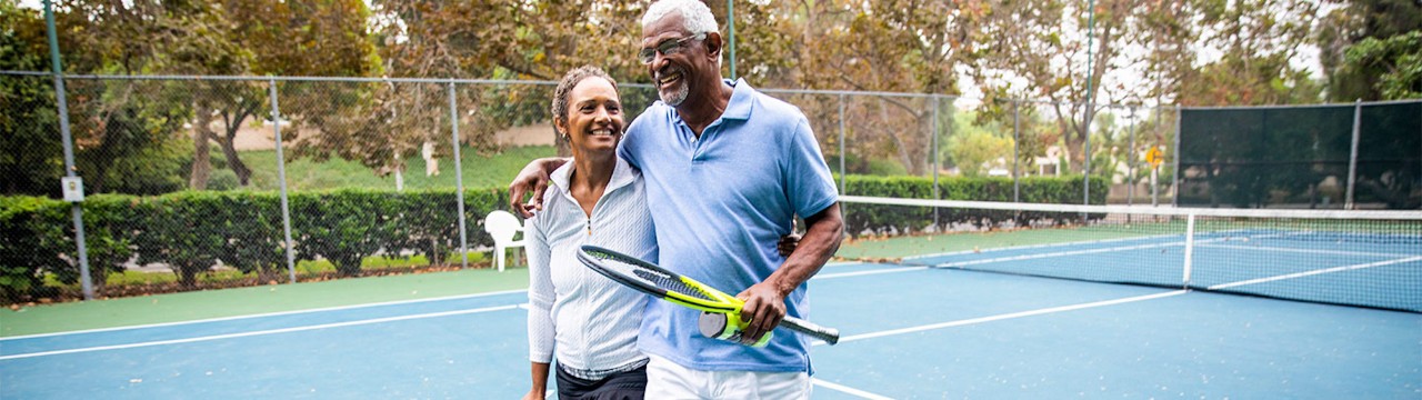 Older couple playing tennis.