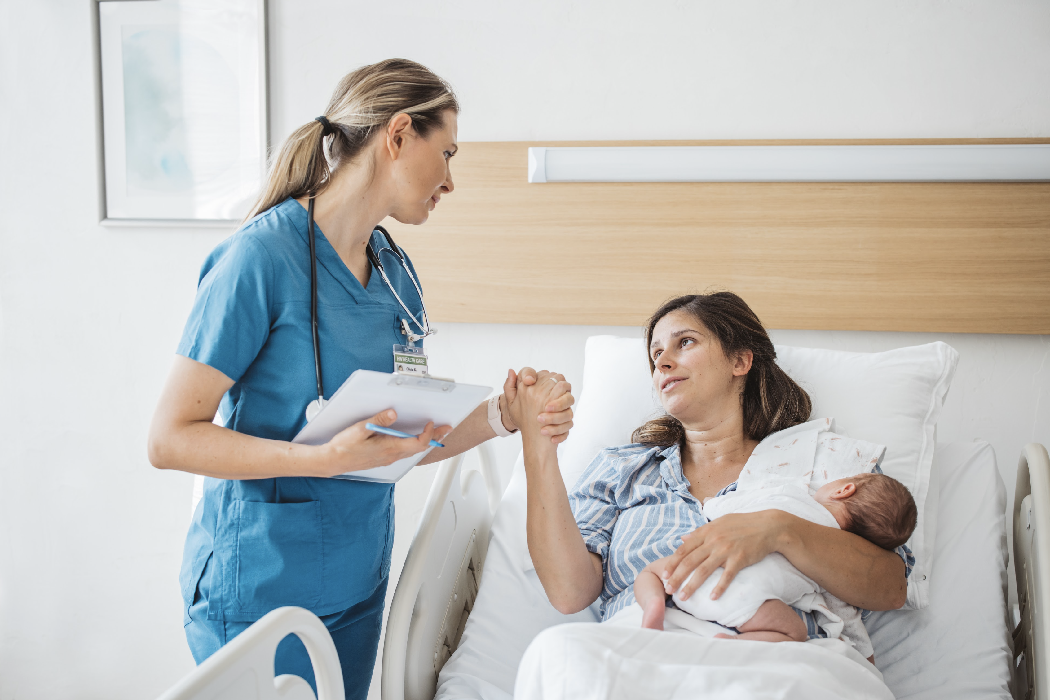mother and baby in hospital bed talking with nurse