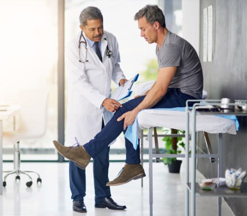 Doctor with patient, examining knee pain
